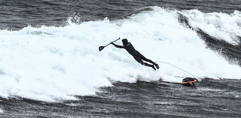 Paddleboarder catching air amidst ocean waves