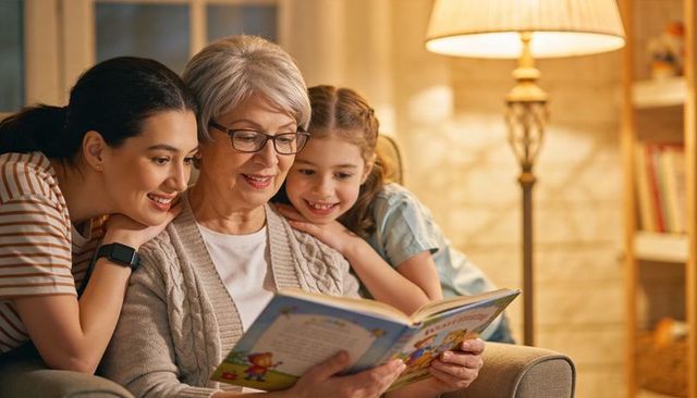 Grandmother reading bedtime story with daughter and granddaughter, cozy multigenerational bonding