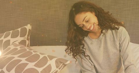 Woman relaxing on bed with cozy pillows and warm atmosphere