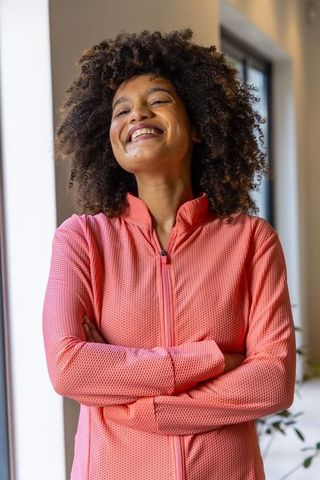 African american woman smiling in coral athleisure jacket, confident lifestyle portrait