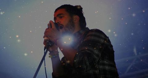 Moody concert vocalist singing into vintage mic with blue haze and lens flare