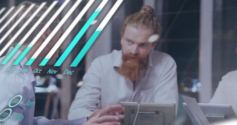 Bearded man with topknot leading digital data review through glass conference room