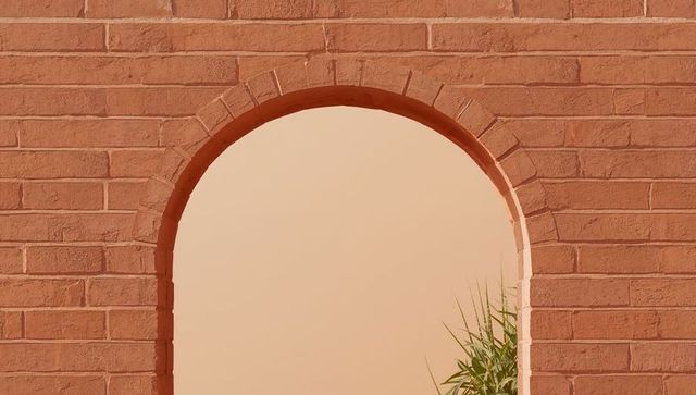 Terracotta brick archway with beige niche and green plant minimalist architectural detail