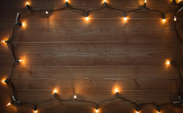 Christmas lights arranged on a wooden plank, creating a warm and festive atmosphere. Ideal for holiday-themed designs, greeting cards, social media posts, and seasonal advertisements. The rustic wooden background adds a cozy and inviting touch, perfect for winter and Christmas-related projects.