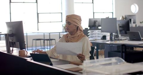 Professional woman analyzing document at office workstation