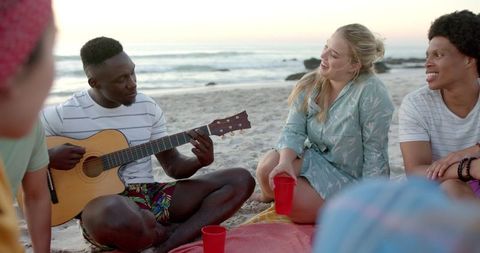 Summer Beach Gathering with Guitar Playing Friends at Sunset