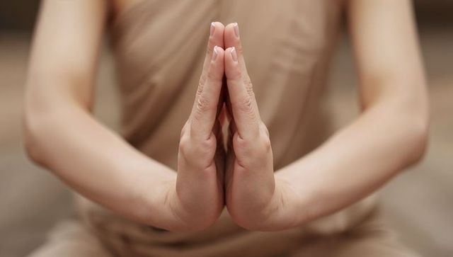 Pressing hands together in namaste gesture showing manicured nails and mindful meditation