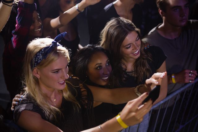 Group of friends watching and taking photograph of performer in club
