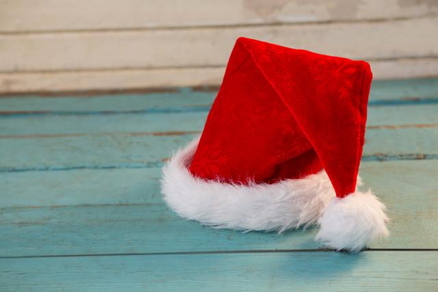 Santa hat resting on a rustic wooden plank, evoking a festive and cozy holiday atmosphere. Ideal for Christmas-themed promotions, holiday greeting cards, festive decorations, and seasonal marketing materials.