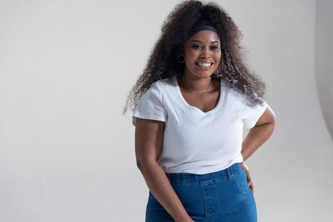 Mid-adult african american woman smiling and posing in studio wearing white top and jeans