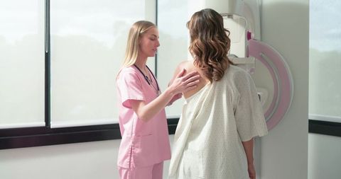 Female Technician Guiding Patient Through Mammogram Screening in Clinic