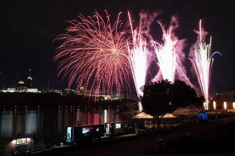 Spectacular Fireworks Exploding Over Riverside Cityscape at Night