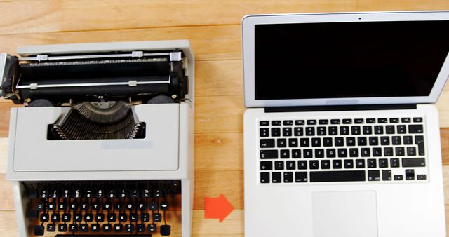 A vintage typewriter sits beside a modern laptop on a wooden table, symbolizing the evolution of technology in writing. The contrast between the two devices highlights the significant advancements in how we create and share information.