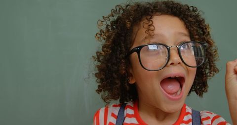 Excited Boy with Curly Hair and Glasses Wearing Striped Shirt - Download Free Stock Images Pikwizard.com