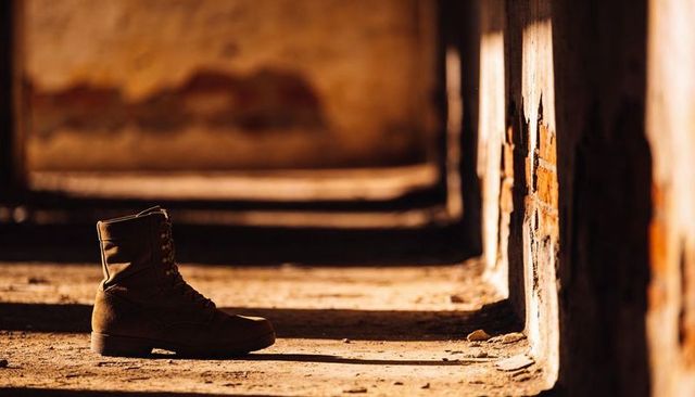 Lone combat boot casting long shadow in abandoned corridor with warm sunlight