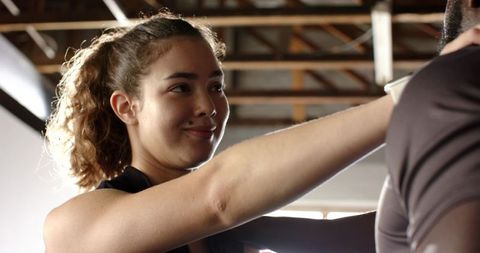 Female trainer guiding client with posture in bright gym