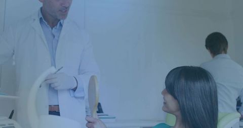 Dentist consulting woman holding mirror during dental exam in modern clinic
