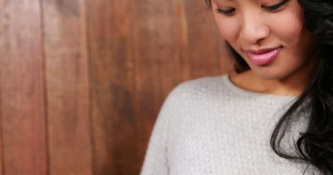 Smiling Woman in White Sweater Against Wooden Background