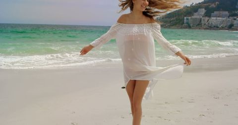 Joyful Woman in White Dress Dancing on Sunny Beach