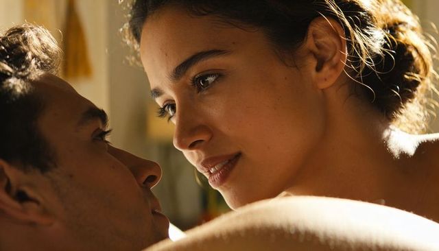 Latina woman leaning over partner in warm morning light closeup romantic intimacy