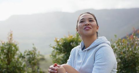 Woman relaxing on mountain hillside appreciating nature's tranquility