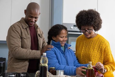 Family preparing fresh produce and pantry jars together in cozy modern kitchen