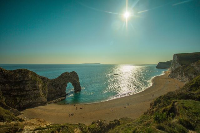 Sunny Coastline with Natural Rock Arch and Sandy Beach - Download Free Stock Photos Pikwizard.com