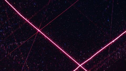 Crossing magenta neon laser beams over dark void with particle glare for cyberpunk design