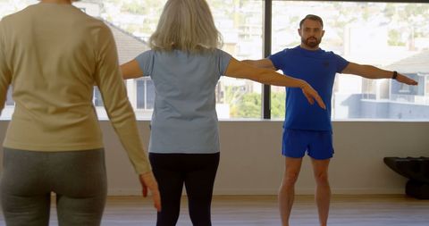 Diverse Adults Engaging in Yoga Class Led by Male Instructor