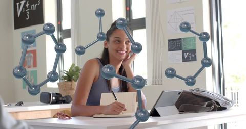 Teen Student Writing Notes Studying Chemistry with 3D Molecule Models in Classroom