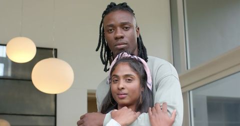 African American man embracing Indian woman in modern interior, intimate couple lifestyle portrait