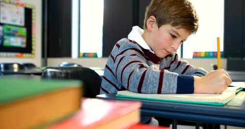 Young Boy Writing in Classroom Setting with Notebooks - Download Free Stock Images Pikwizard.com