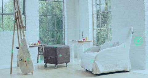 Bright minimalist art corner offering white slipcovered armchair, easel, paint jars