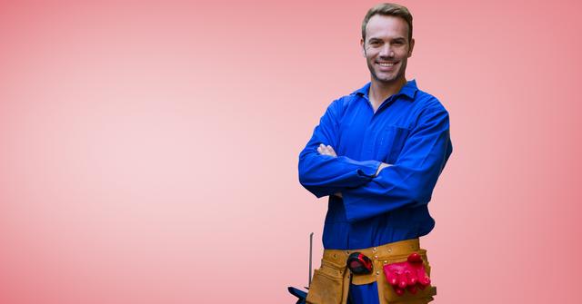 Handyman in blue uniform standing with arms crossed, smiling confidently, wearing tool belt with various tools against a red background. Ideal for use in advertisements related to home repair services, construction companies, and service industry promotions. Can be used on websites, brochures, and flyers targeting maintenance and home improvement.