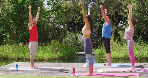 Group yoga session in park with instructor leading