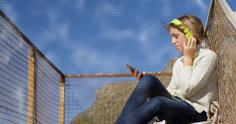Teen listening to music on green headphones relaxing on scenic observation deck