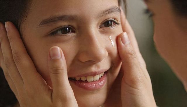 Gentle comfort: caregiver holding tearful child face with reassuring smile and soft touch