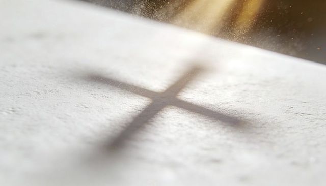 Casting sunlit cross shadow over pale textured surface with floating dust motes