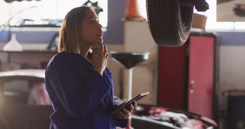 Female Mechanic Analyzing Car Repair in Auto Workshop