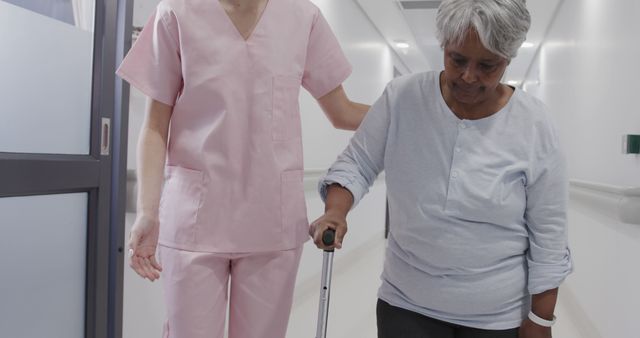 Nurse Assisting Elderly Woman with Walking Stick in Hospital Corridor - Download Free Stock Images Pikwizard.com