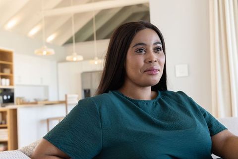 Serene african american woman relaxing on sofa in minimalist open-plan kitchen