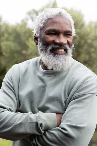 Mature african american man smiling with arms crossed wearing sage sweatshirt outdoors