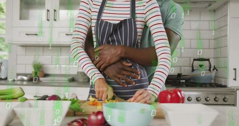 Couple cooking embrace while chopping vegetables in modern kitchen with binary overlay