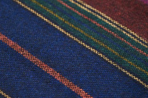 Wool textile featuring diagonal multicolor stripes, rich blue knit with textured weave
