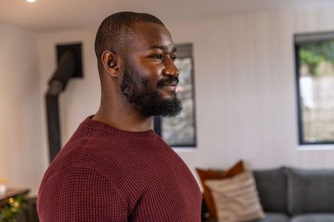 African american man smiling in cozy living room wearing maroon sweater lifestyle portrait