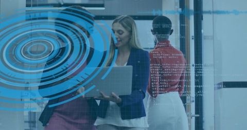 Businesswomen presenting data on laptop with futuristic HUD overlay in modern office