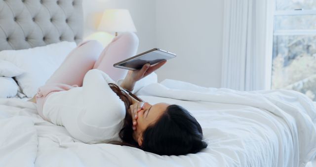 Woman Relaxing on Bed While Using Tablet in Bright Bedroom - Download Free Stock Images Pikwizard.com