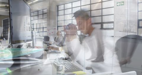 Overwhelmed businessman working at cluttered desk in modern office, blurred motion stress