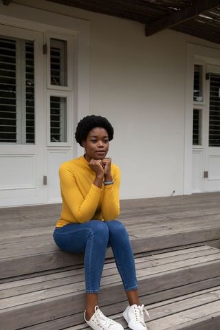 Contemplative Woman in Casual Wear Sitting on Rustic Porch Steps