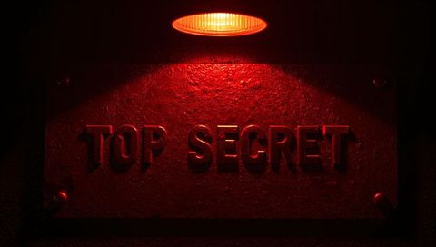 Glowing red top secret metal plaque under overhead lamp dramatic security sign